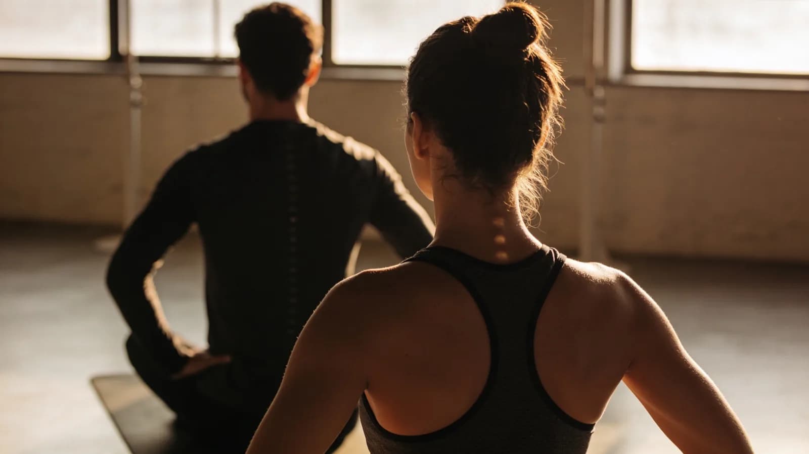 Deux personnes en gainage, vues de dos à contre-jour